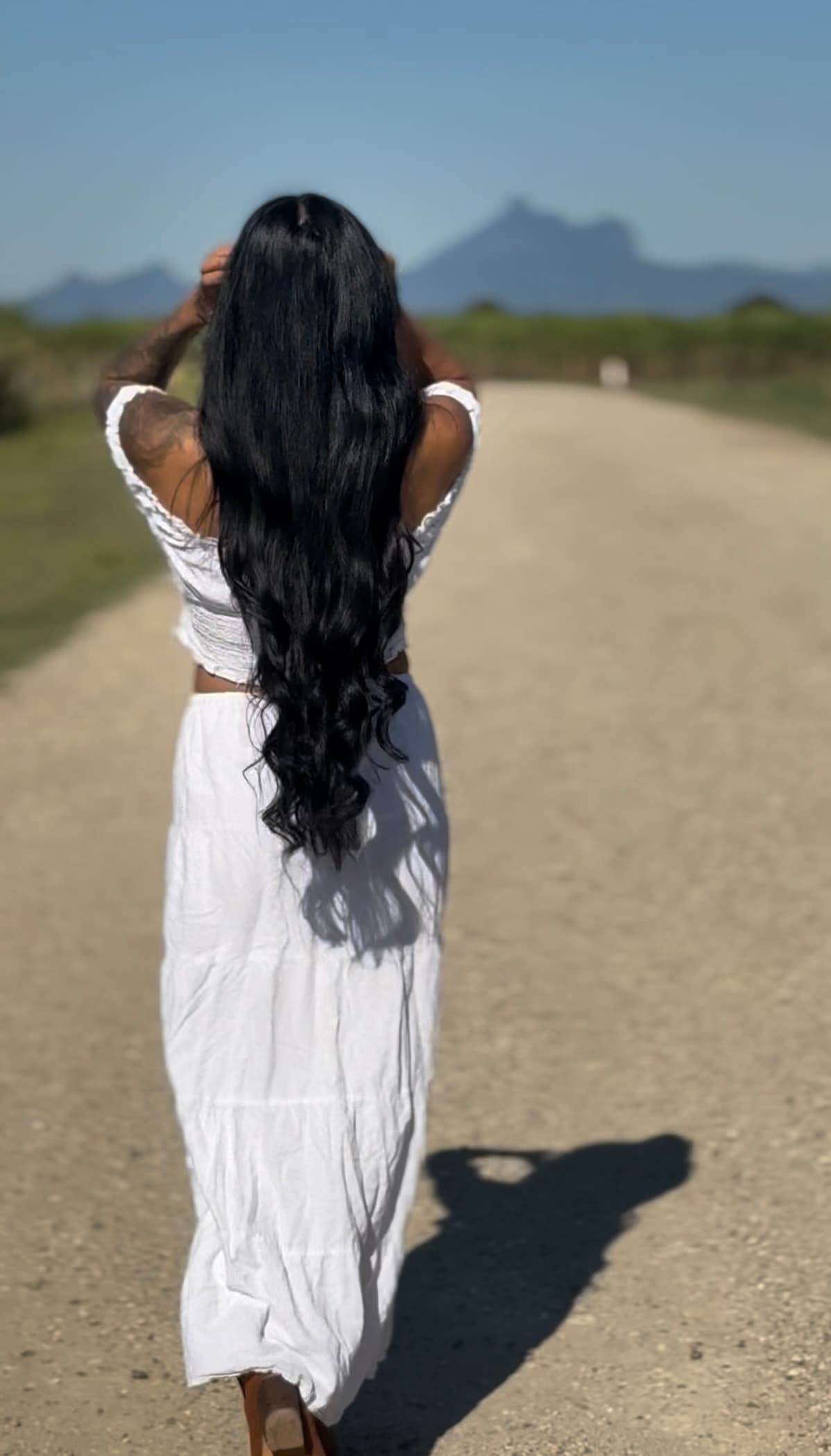 Sheree walking along a country road with mountains in the distance